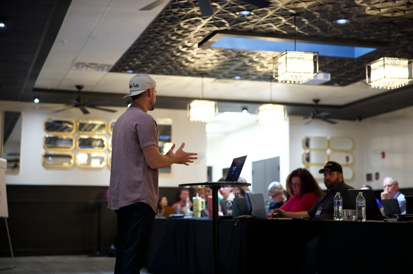 Presenter addressing a corporate group seated at laptops during a meeting at The Hive